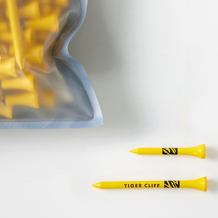 Bag of yellow golf tees and two loose Tiger Cliff Tee - Wood (75 pack) with tiger stripes logo.