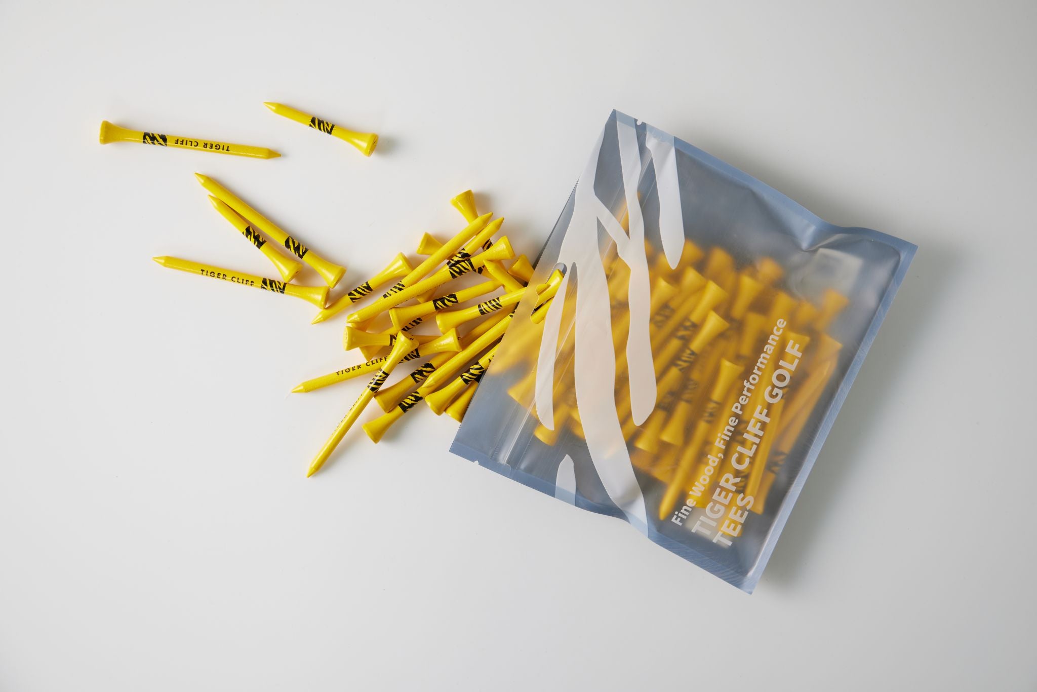 Yellow Tiger Cliff golf tees spilling from branded packaging.
