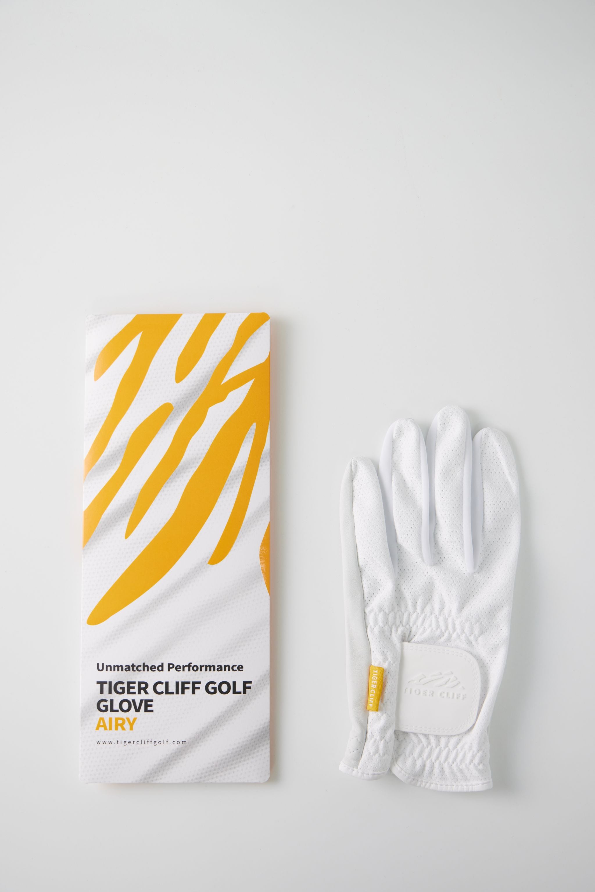 Tiger Cliff Golf Glove Airy next to its packaging on white.