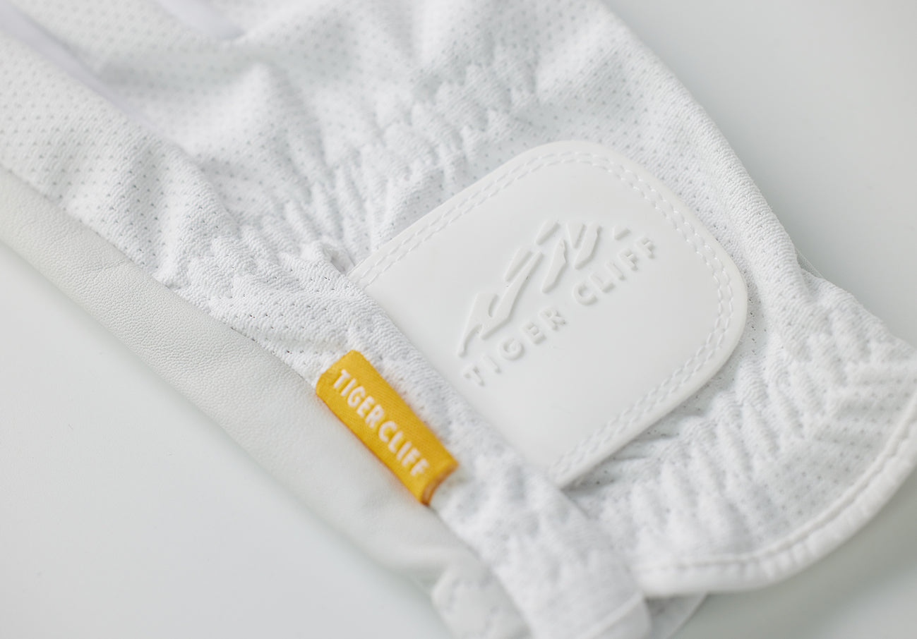 Close-up of a white Tiger Cliff glove with a yellow tag.