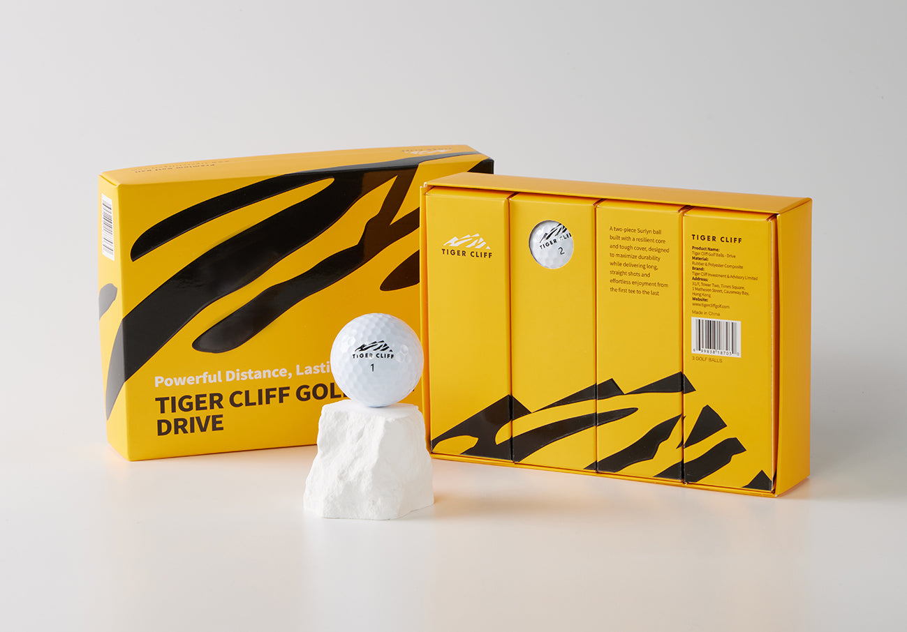 Boxed Tiger Cliff Golf Drive balls with one ball on a white rock.