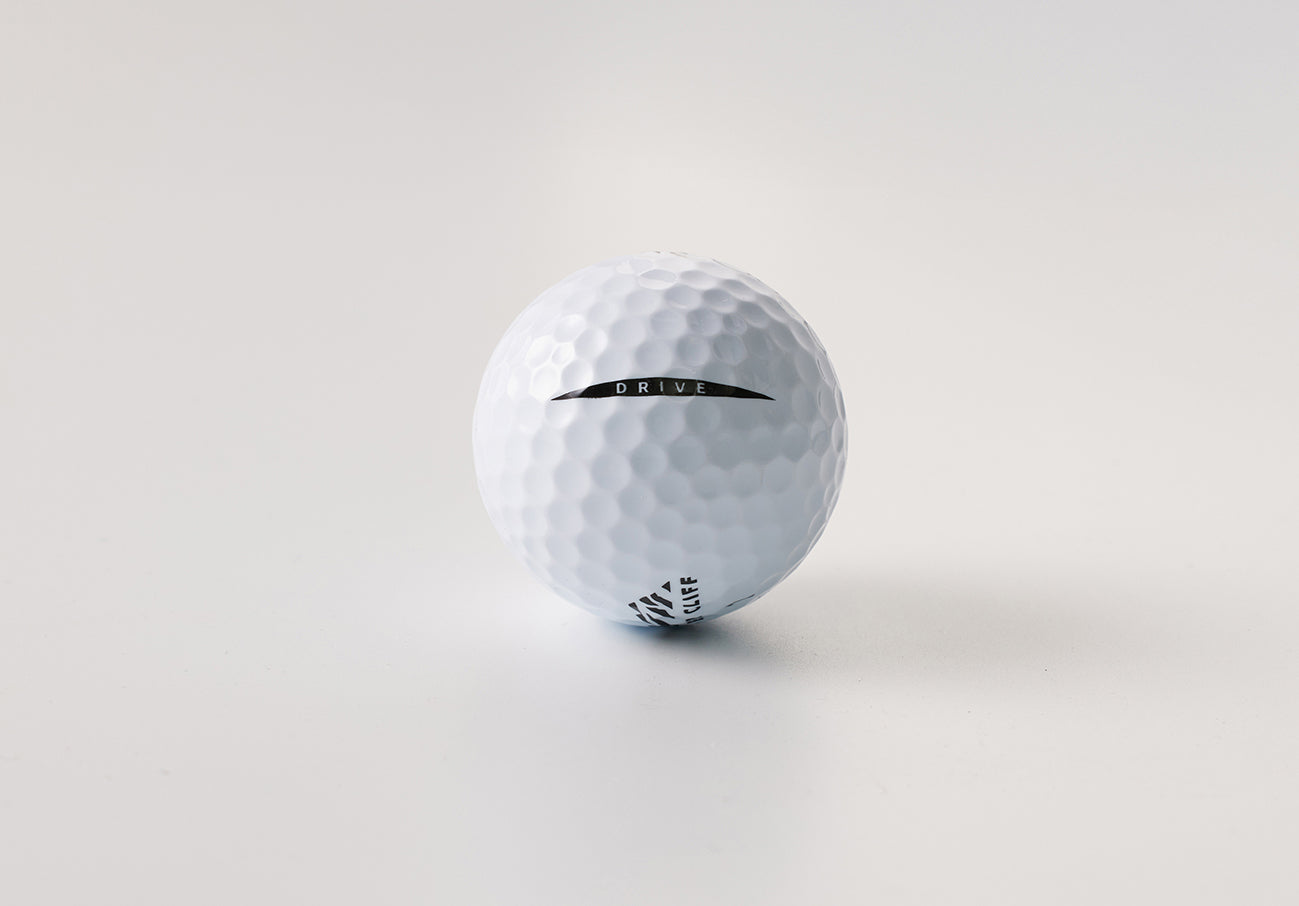 Close-up of a white golf ball with "DRIVE" and other markings on a white background.