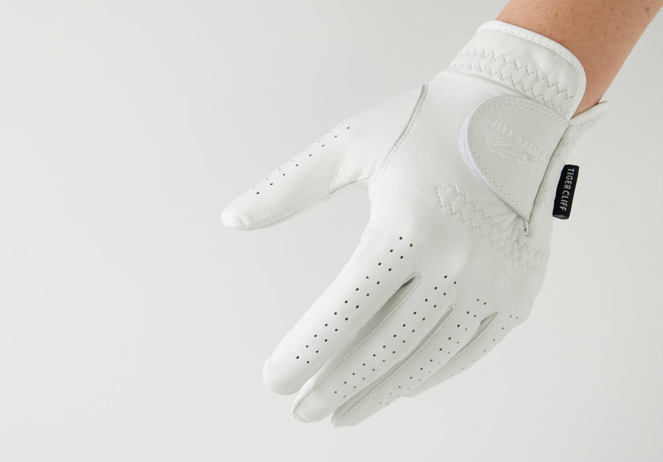 Hand wearing a white LAMBSKIN golf glove with ventilation holes.