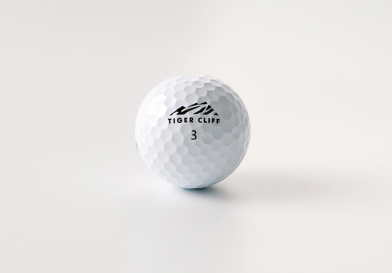 Close-up of a white Tiger Cliff golf ball with number 3 on a white surface.