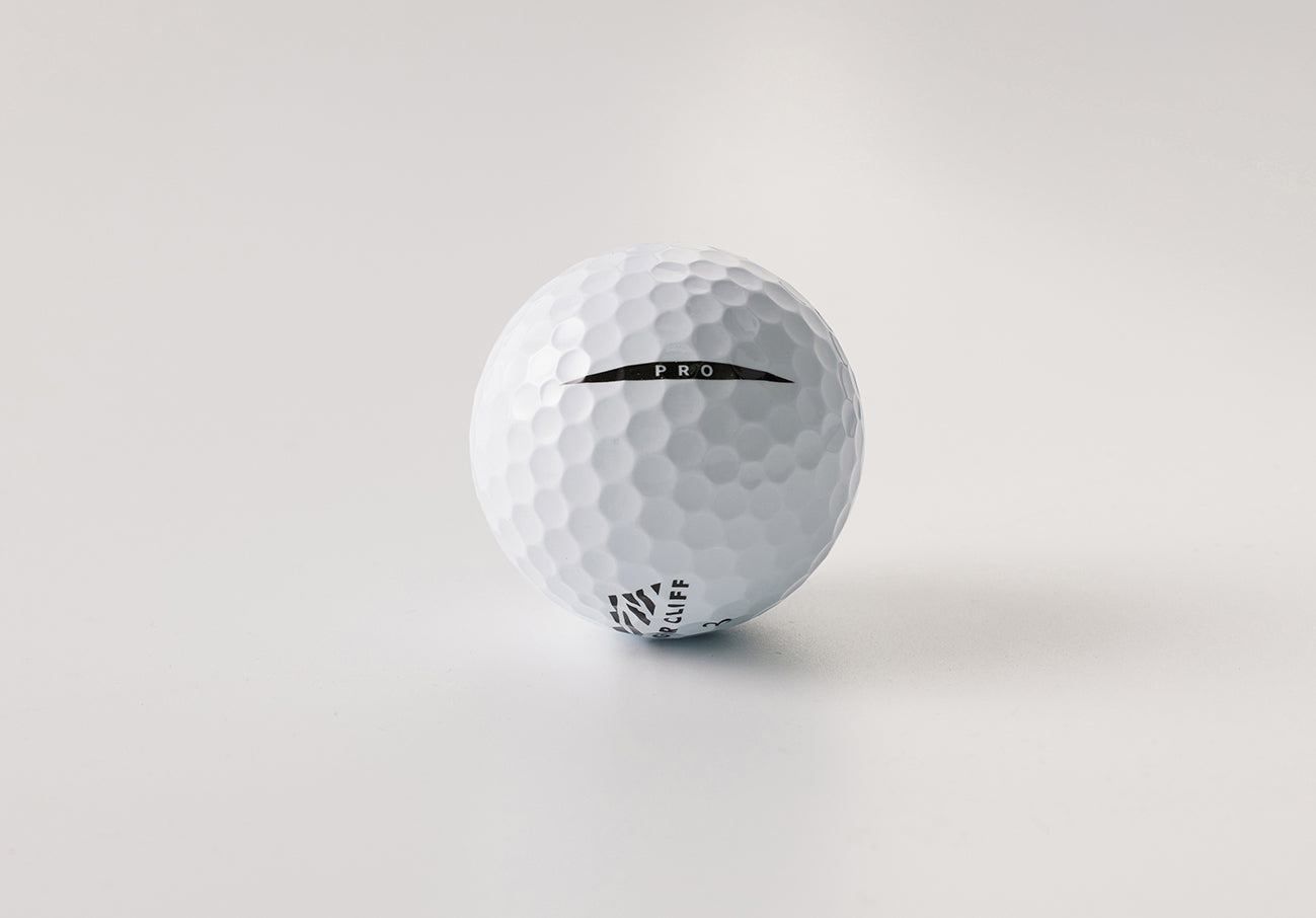 White "PRO" golf ball on a white surface.