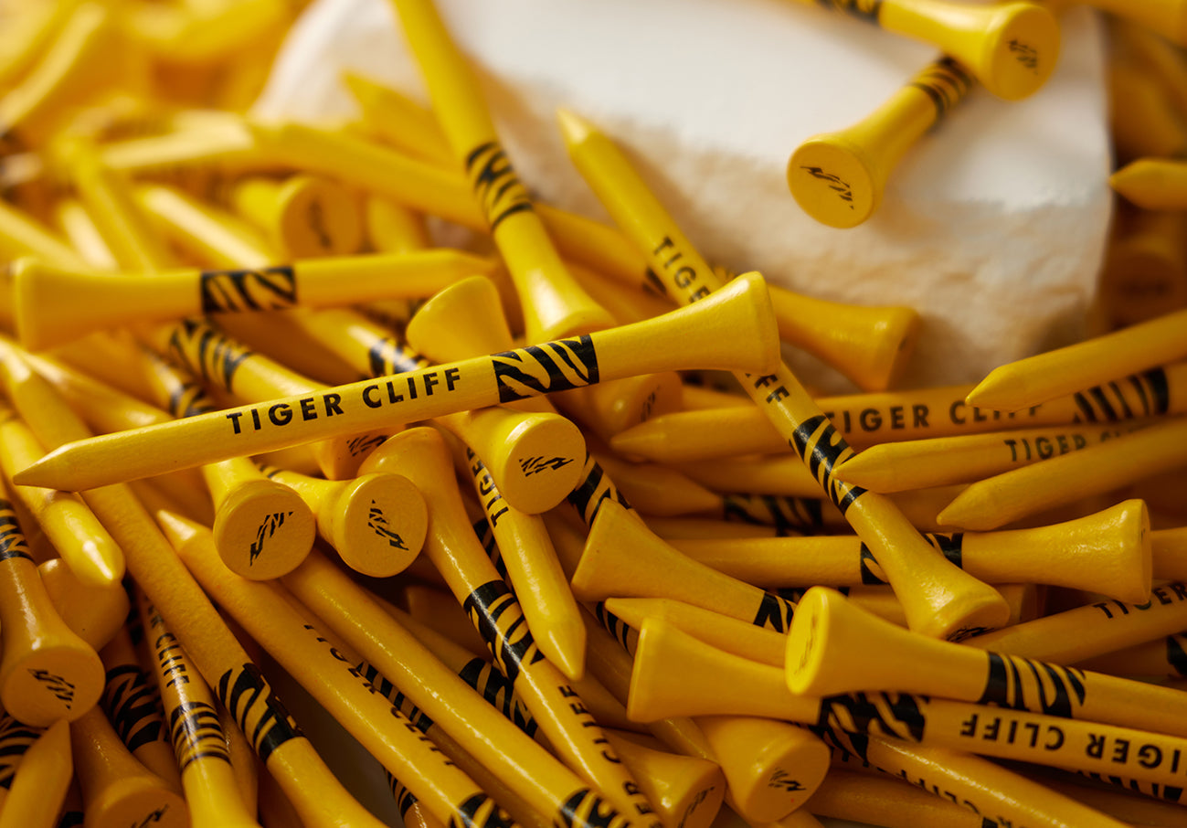 Pile of yellow "Tiger Cliff" golf tees with black stripes.
