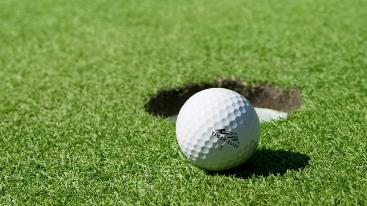 Golf ball on the edge of a golf hole with green grass in the background